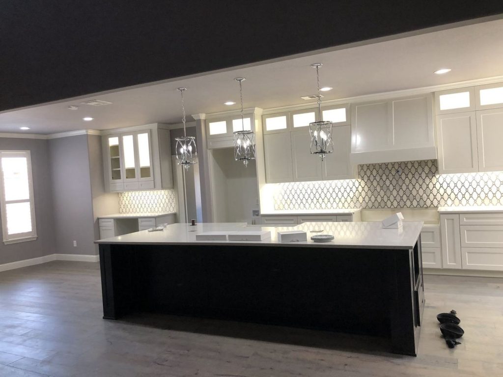 Black painted kitchen island with white cabinets and tile backsplash