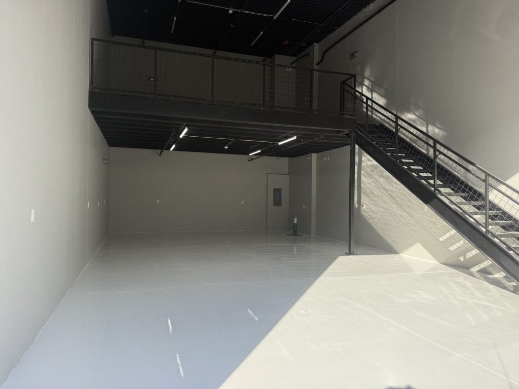 Finished commercial warehouse with painted walls, black ceiling and mezzanine
