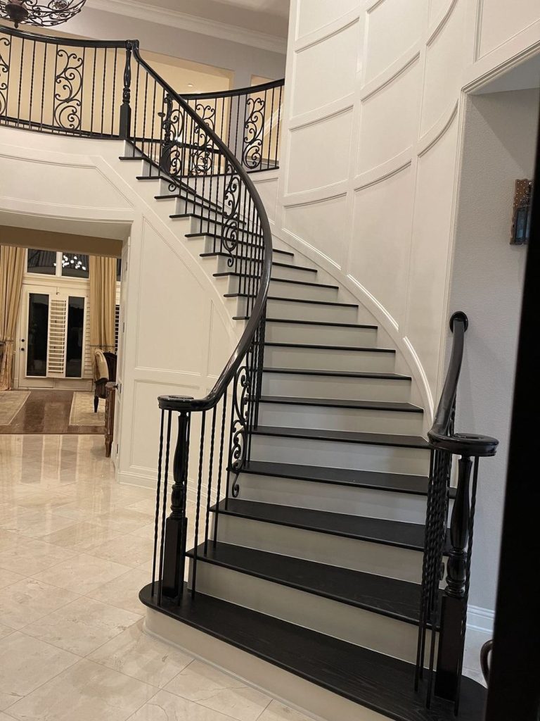 Curved staircase with dark stained treads and iron railing