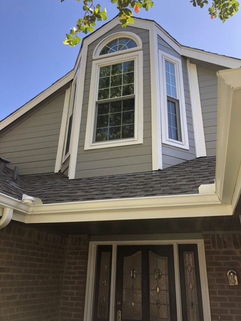 Arched window gable with gray siding and white trim after painting