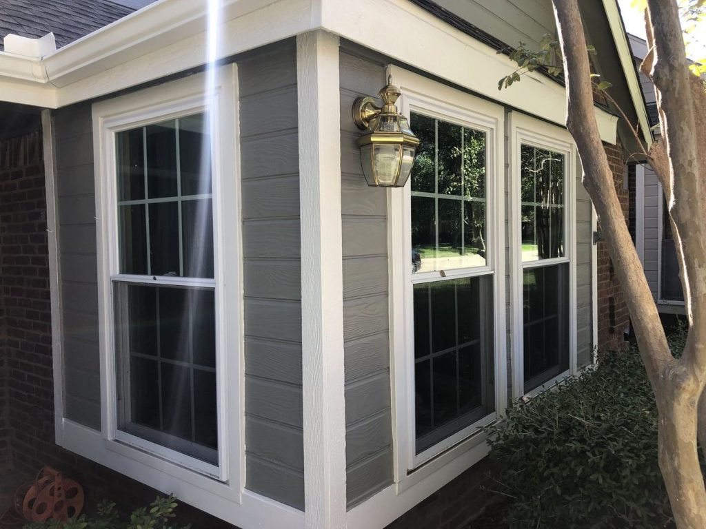 Bay window with gray siding and white trim after painting