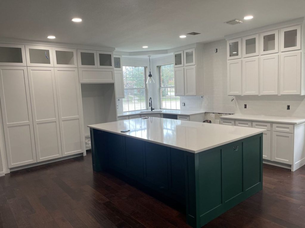 Dark green painted kitchen island with white cabinets and glass uppers