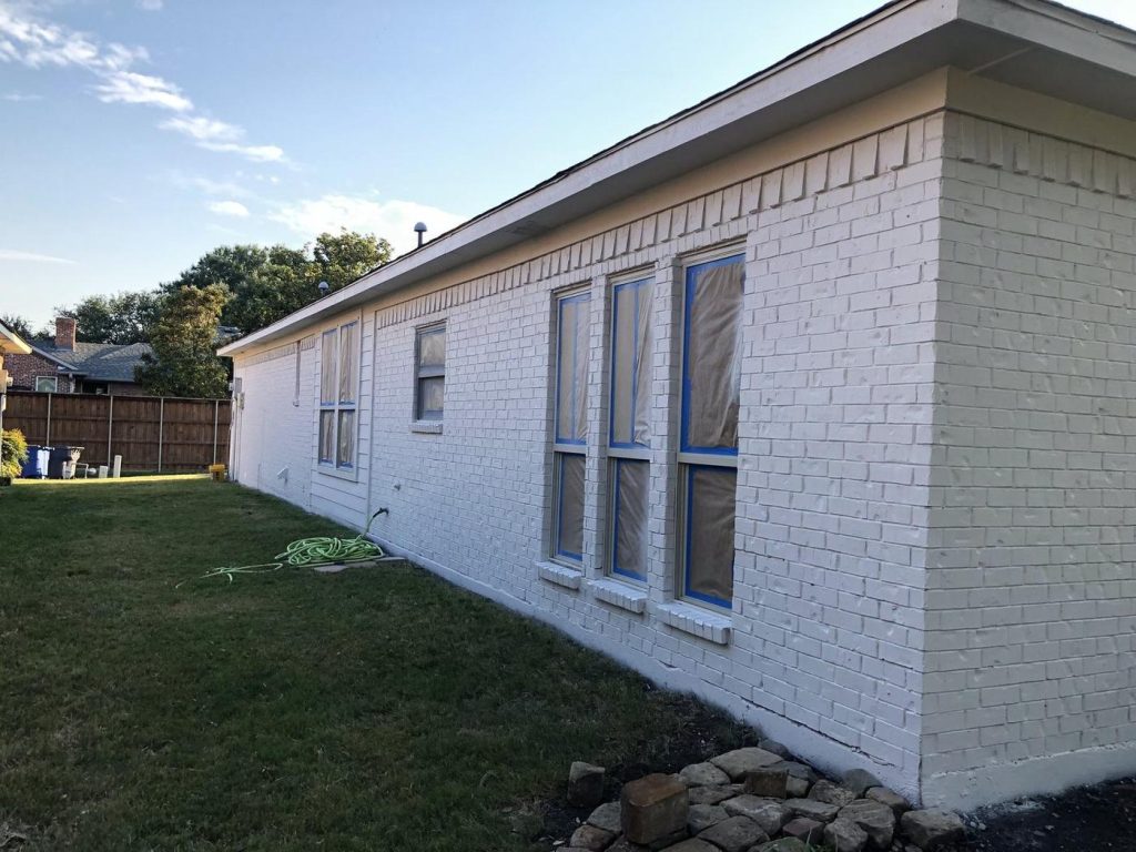 Side of a home with freshly painted white brick and new window trim