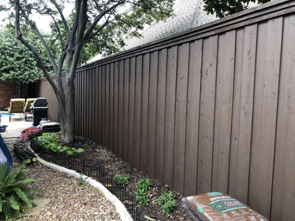Stained backyard privacy fence along a garden bed