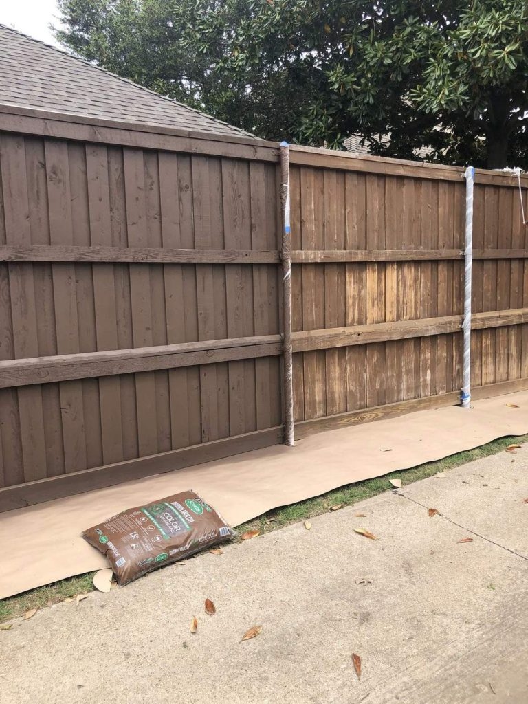 Wood privacy fence partly stained, showing old and new finish